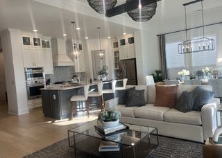 Model Home A modern open-concept living space with a sleek kitchen, cozy dining area, and elegant pendant lighting.