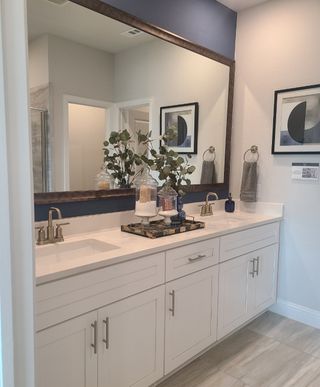 Model Home A modern bathroom featuring a double vanity, elegant fixtures, and contemporary artwork.