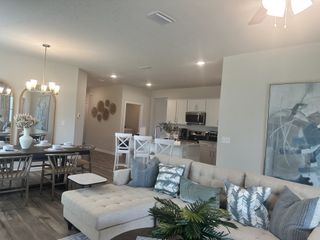 A cozy living and dining area featuring a plush sectional, elegant chandelier, and stylish decor in neutral tones.