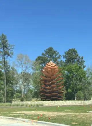 A striking pine cone sculpture amidst natural greenery in Evergreen by Chesmar Homes (Conroe, TX).