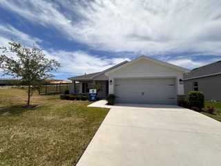 Street view A modern white home with a spacious driveway and manicured lawn in Geneva Landings by Highland Homes of Florida (Davenport, FL).