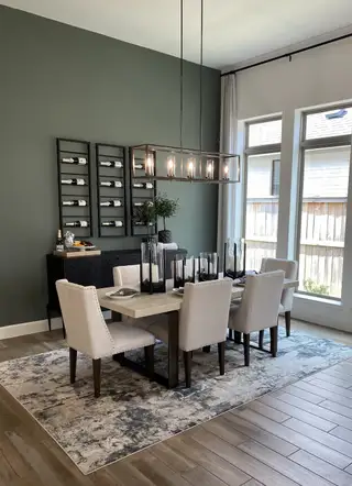 A sophisticated dining space with a green accent wall, wine racks, and a statement chandelier.