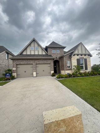 A charming brick home with gabled roof and driveway in Elevon by Pacesetter Homes (Lavon, TX).