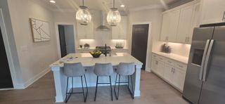 Model Home A modern kitchen featuring a spacious island, pendant lighting, sleek cabinets, and stainless steel appliances.