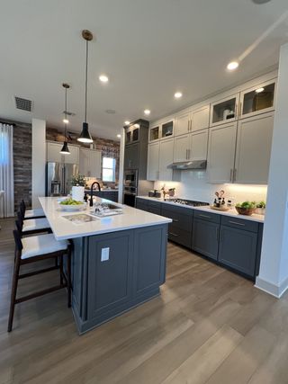 Model Home A gourmet kitchen featuring two-tone cabinetry, a spacious island with bar seating, and elegant pendant lighting for a sophisticated touch.