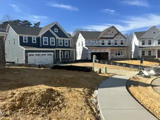 A contemporary blue home with a garage in Highland Ridge by Ryan Homes (Willow Spring, NC), adjacent to ongoing construction.