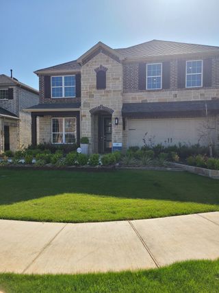 Street view A beautiful stone and brick home with lush landscaping in Spiritas Ranch by Pulte Homes (Little Elm, TX).