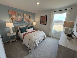 Model Home A cozy bedroom with a modern bed, abstract art, soft lighting, and a large window offering natural light and scenic views.