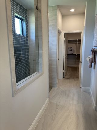 Model Home Elegant bathroom with sleek tiled surfaces, a walk-in shower, and soft lighting creating a serene ambiance.