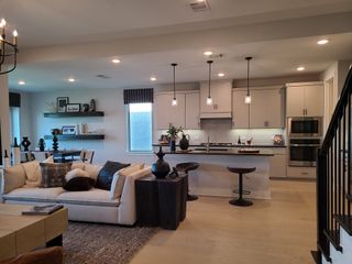 A modern open-concept living area with a chic kitchen, cozy seating, and stylish pendant lighting.