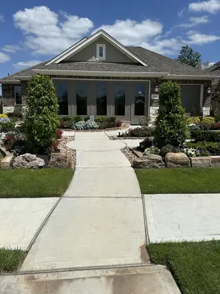 Street view A charming stone-accented home with lush landscaping in Sorella by M/I Homes (Tomball, TX).