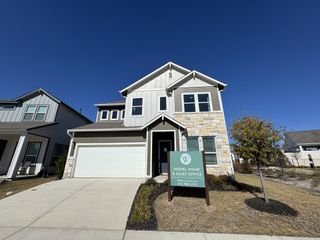 A modern home with stone accents and a pristine driveway in Wellspring by Clark Wilson Builder (Round Rock, TX).