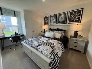 Model Home A cozy bedroom with floral artwork, modern lamps, and a stylish black-and-white bedding set.