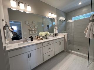 A modern bathroom featuring a sleek double vanity, elegant lighting, and a spacious glass-enclosed shower.