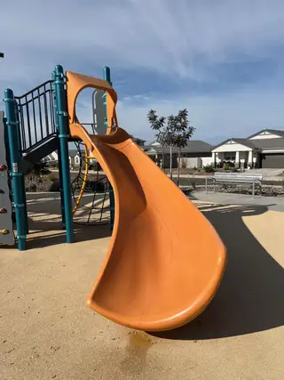 A vibrant playground with a slide and nearby homes in Radiance At Superstition Vistas by D.R. Horton (Apache Junction, AZ).