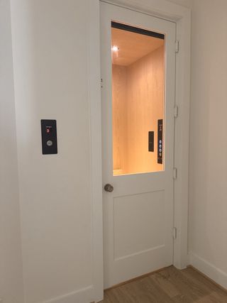 A modern home elevator with a sleek wood interior and minimalist door design.