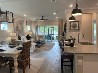 A cozy open-plan living area with modern lighting, plush seating, and a sleek kitchen bar with elegant decor.