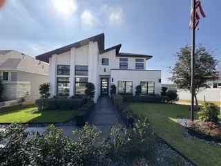 Model Home A sleek, contemporary exterior with sharp rooflines, large windows, and manicured landscaping in Esperanza by Perry Homes (Boerne, TX).