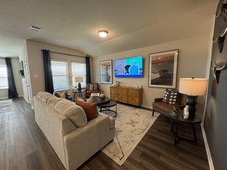 Model Home A cozy living room with a neutral sofa, stylish decor, and a mounted TV, complemented by wood flooring and soft lighting.