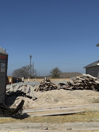 A construction site with scattered materials and an unfinished foundation between two existing homes.