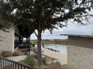 Community Amenities A serene community pool with cozy seating in Whisper Valley by Pacesetter Homes, offering relaxation in Manor, TX.