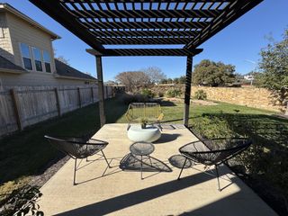 Model Home A cozy outdoor patio with stylish chairs and a pergola, perfect for relaxation and entertaining.