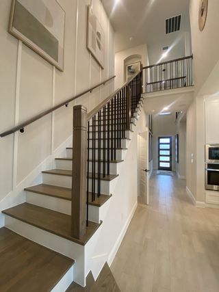 Model Home A modern staircase with sleek wooden steps and iron railings, enhanced by abstract wall art and bright lighting.