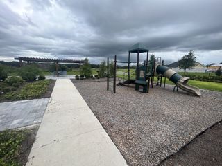A charming playground with lush greenery in Oakfield at Mount Dora Cottage Series by David Weekley Homes (Mount Dora, FL).
