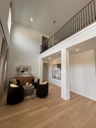 A spacious living area with high ceilings, elegant décor, and cozy seating, enhanced by natural light and modern art.