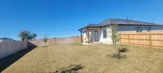 Model Home A charming backyard with a patio and fenced lawn in Mesa Vista by CastleRock Communities (Von Ormy, TX).