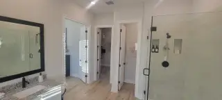 A modern bathroom with a spacious shower, elegant tile work, and a sleek granite countertop.