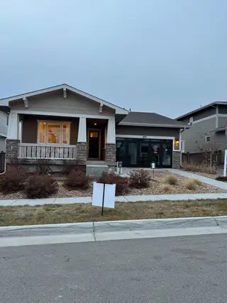 A charming ranch-style home with a cozy porch and landscaped yard in Villages at Prairie Center by Richmond American Homes (Brighton, CO).