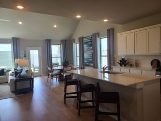 Open-concept living area with cozy seating, sleek kitchen island, and abundant natural light from large windows.