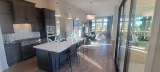 Model Home A modern kitchen with dark cabinets, a large island, pendant lights, and an open view to a stylish dining area.