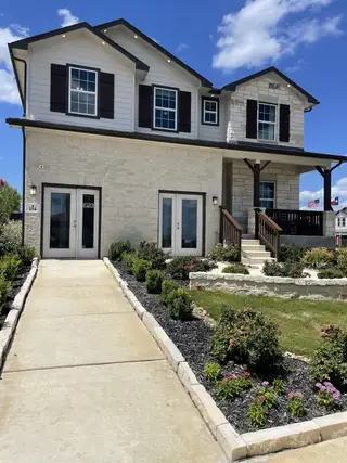 Street view A charming two-story home with rustic shutters and manicured landscaping in Arcadia Ridge by CastleRock Communities (San Antonio, TX).