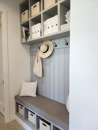 A cozy mudroom bench with baskets, hooks, and upper shelving for organized storage and decor.