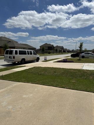 A serene suburban street view in Willow Trace 45' by Century Communities, featuring spacious homes under a bright blue sky (Spring, TX).