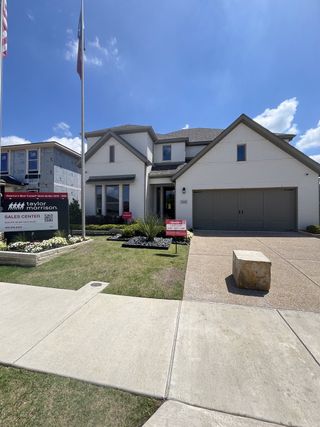 A modern white brick home with sleek lines and a manicured garden in Stoneridge by Taylor Morrison (Melissa, TX).
