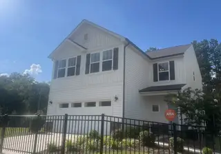 A charming white home with black shutters and a fenced yard in Aubreywood by True Homes (Charlotte, NC).