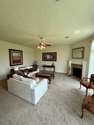 A cozy living room featuring a plush carpet, elegant fireplace, and tasteful art, creating an inviting atmosphere.