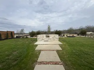Street view A serene backyard with lush grass and a stone fire pit area in Megan's Landing Half Acre by Perry Homes (San Antonio, TX).