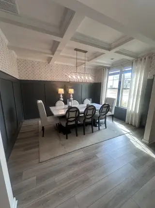 A sophisticated dining space with a coffered ceiling, large windows, and sleek furniture in Dacula, GA.