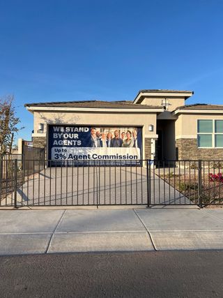 Street view A modern stone-accented home with gated driveway in Copper Falls by D.R. Horton (Buckeye, AZ).