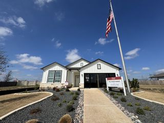 Street view A charming home with rock landscaping and a flagpole in Weltner Farms 50's by View Homes (New Braunfels, TX).