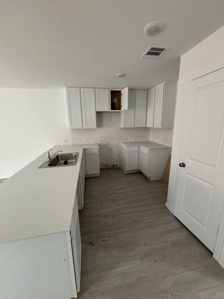 A modern kitchen with sleek white cabinetry, a shiny sink, and light wood flooring.
