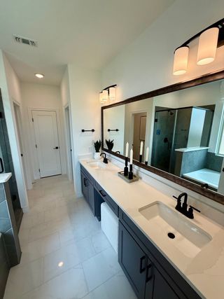 A modern bathroom featuring dual sinks, sleek black fixtures, and elegant lighting on a long vanity.