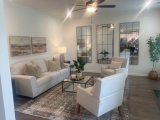 A cozy living room with a plush sofa, elegant mirrors, and stylish decor on a patterned rug.