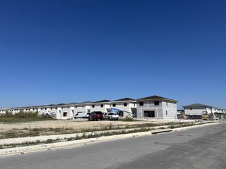A row of modern, white homes under construction in On Alba by Onx Homes, Florida City, FL, against a clear blue sky.