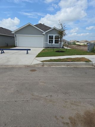 A charming gray home with a neat driveway and lawn in the Durango community by D.R. Horton (Mustang Ridge, TX).