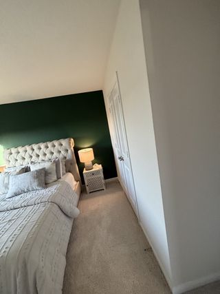 A cozy bedroom with a button-tufted headboard, accent wall, and elegant bedside lamp.
